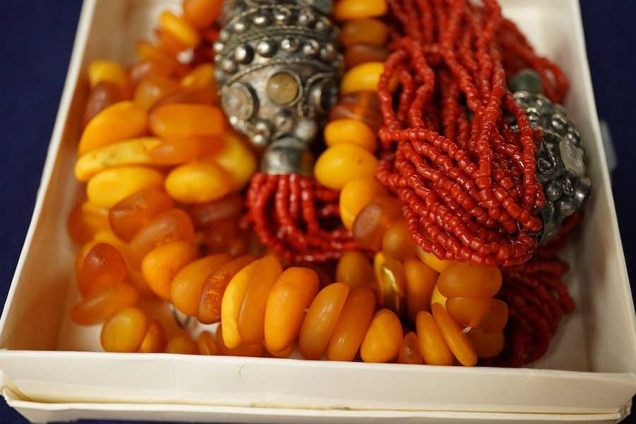 Two necklaces, comprising: a multi-strand coral necklace of torsade design, spaced by beads set with various hardstones, length 73cm; and an amber bead necklace, length 57cm